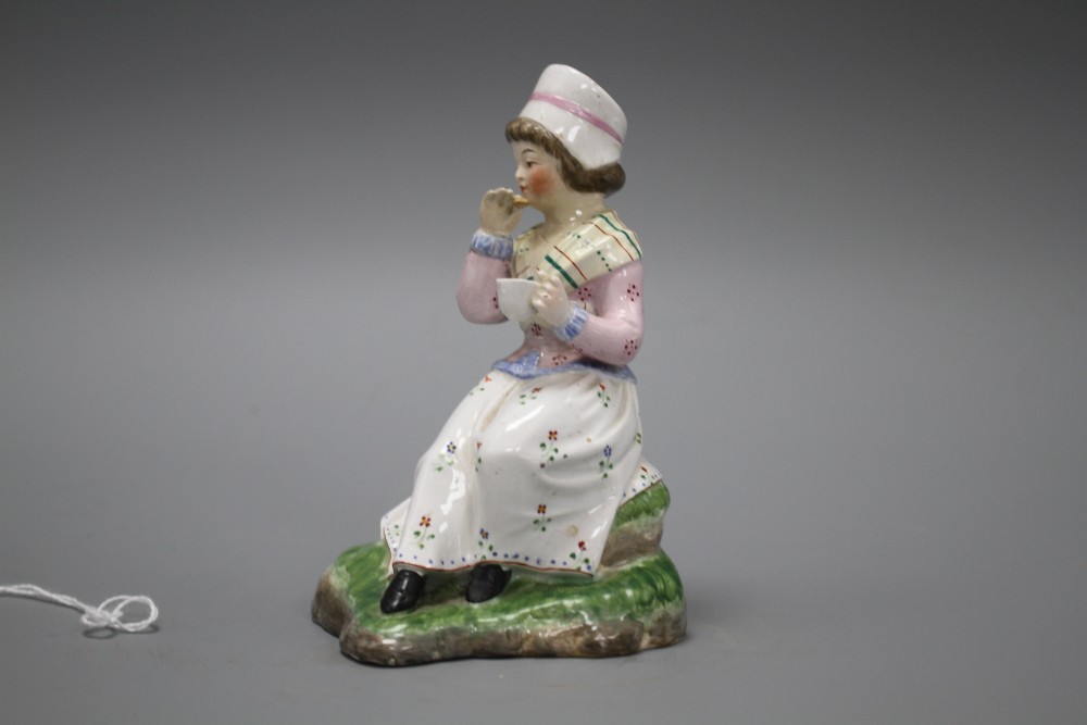 A 19th century Staffordshire figure of a seated young lady taking tea, height 13cm